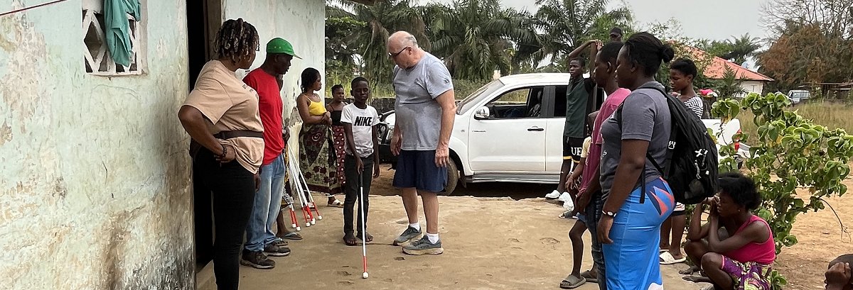 Picture of Steve Hoyt who is a Orientation and Mobility instructor, giving instruction to a group of blind people with the white cane in Liberia, Africa.