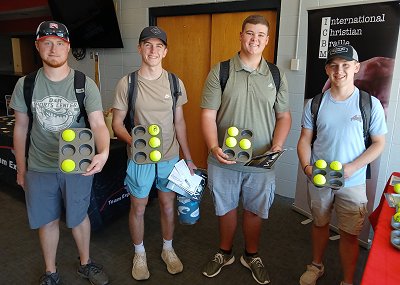 Picture of four Kentucky Christian University Students that are holding a large muffin tin with tennis balls depicting the first initial of their names.  The gentlemen are holding the letters k, l, h, and m.  This is an event that KCU host for students to get to know missionaries and how they can be involved in mission work.